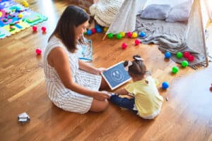 A child therapist sitting on the floor while playing with a child. Our child therapists in Katy, TX can help your child build confidence & resilience. Get started today!