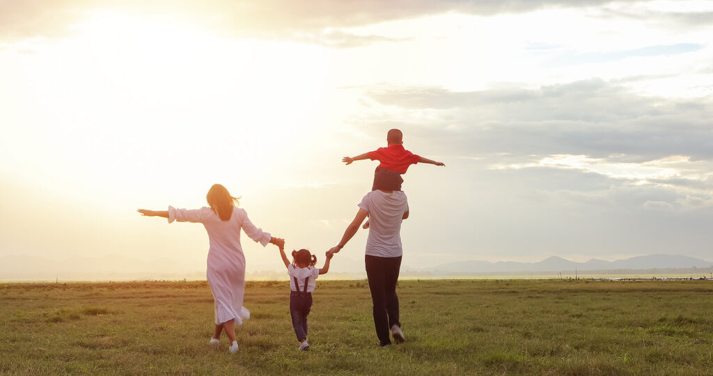 A family running together in a field all holding hands. Our child therapy for anxiety in Katy, TX can help your child thrive. Get started today with child counseling.