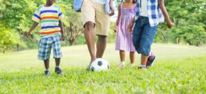 A family kicking around a soccer together. Representing how you can have a healthy co-parenting relationship with the help of our child therapy in Katy, TX. Reach out today.