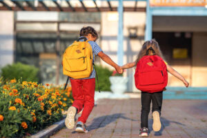 Two children running toward a school building. Our child counseling for anxiety in Katy, TX can help your child want to go to school. Call us today to learn more!