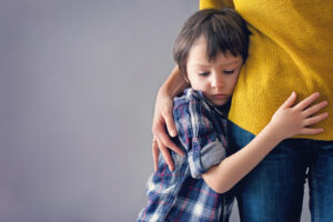 A young boy holding onto his mothers side. This represents childhood separation anxiety & how child therapy can help. Our child therapists in Katy, TX are here to help support your family!