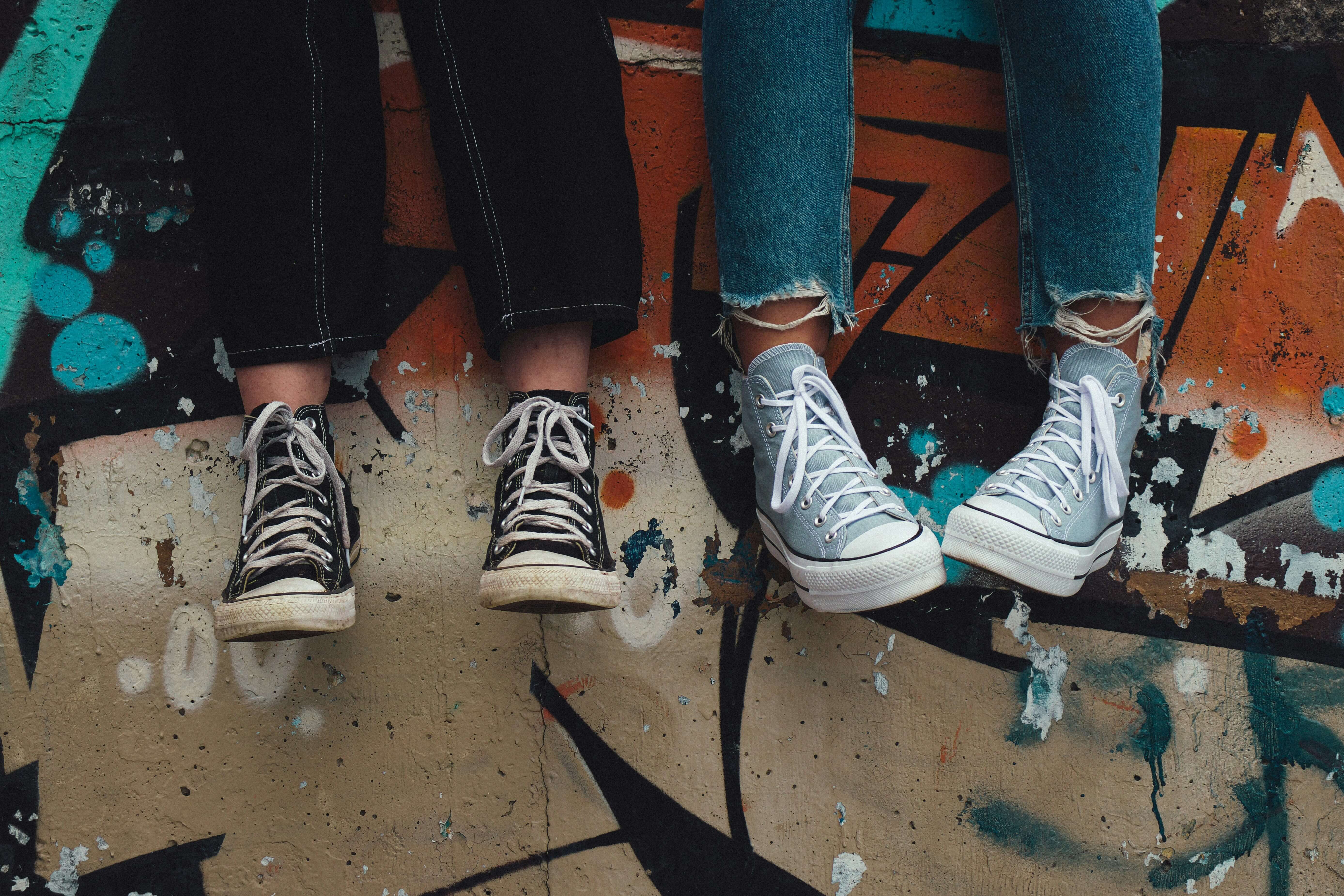 Two pairs of converse shoes hanging over a ledge. LENS Neurofeedback in Katy, TX can help your teen with emotional dysregulation, ADHD & more. Reach out to us today to get started.