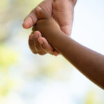 A closeup of a parent's hand holding their child's hand. If you suspect your child has emotional dysregulation, reach out to work with a child therapist in Katy, TX. Call now!