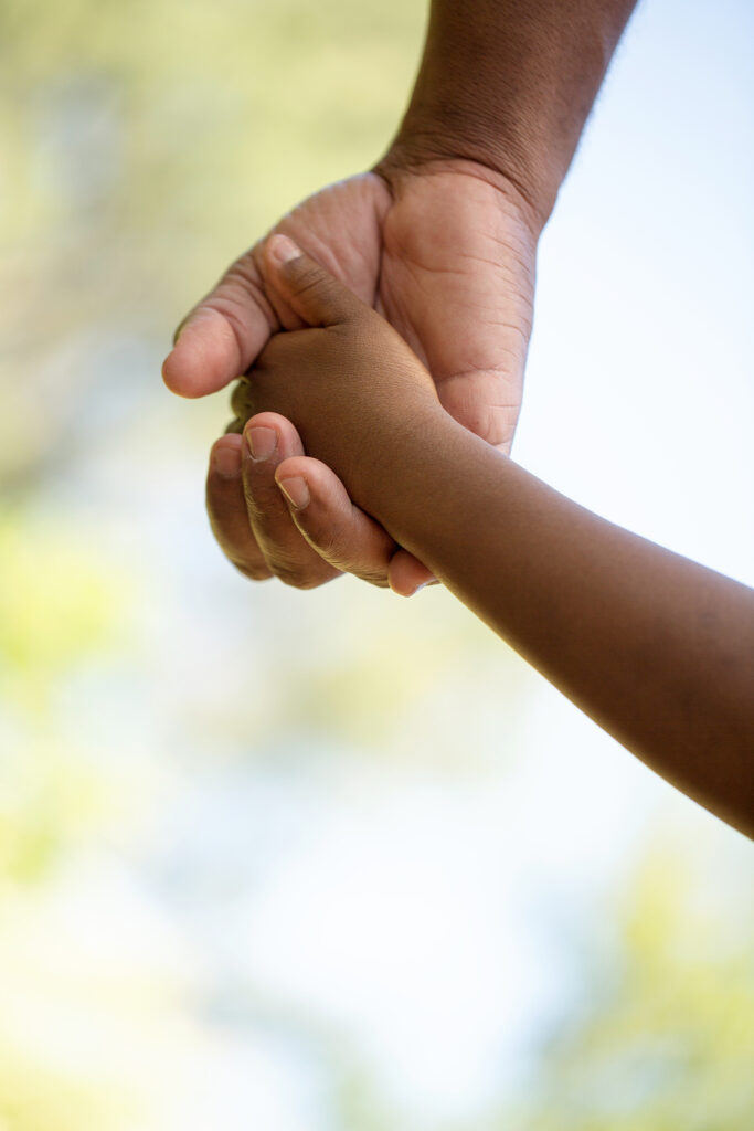 A closeup of a parent's hand holding their child's hand. If you suspect your child has emotional dysregulation, reach out to work with a child therapist in Katy, TX. Call now!