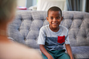 A young boy sitting on a couch talking to a child therapist. To get started with our child therapists in Katy, TX, reach out to us today! We can help support your child's mental well-being. 