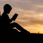 An silhouette of a young boy reading a book in an open area. To leran more about how our child behavioral therapy in Katy, TX, reach out to us today. We can help your family thrive.