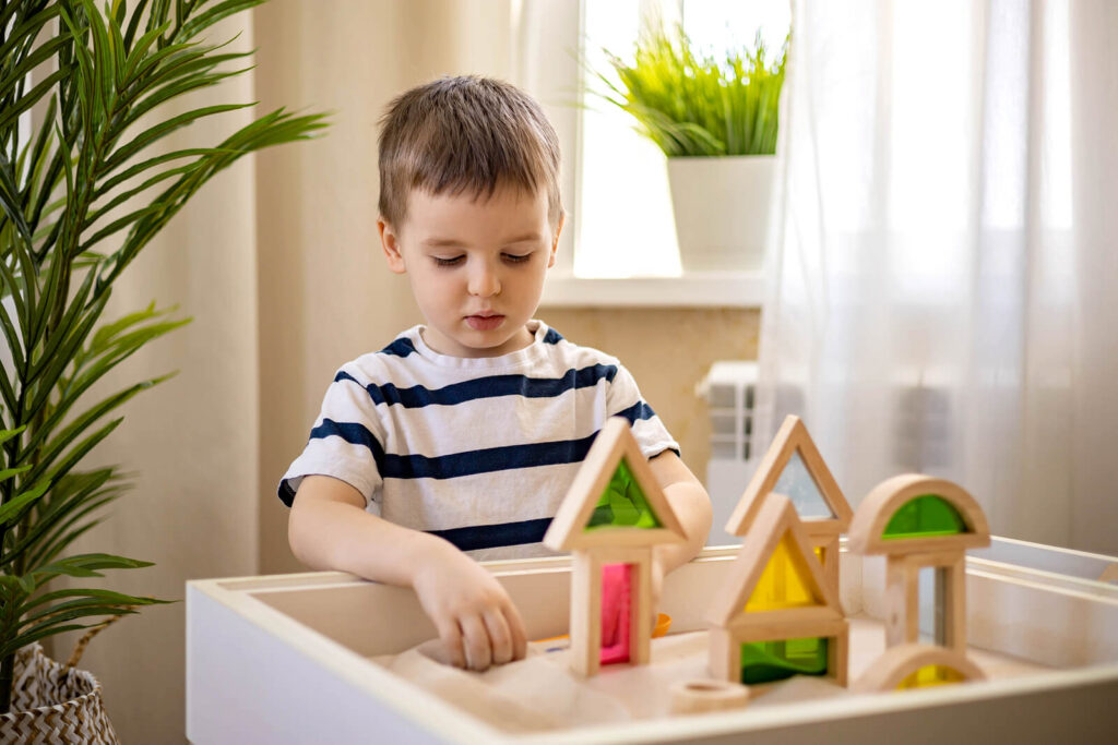 A young boy playing in the sand tray with green & red building blocks. Therapy for children in Katy, TX can help your family flourish. Reach out today to get started with a child therapist.