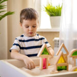 A young boy playing in the sand tray with green & red building blocks. Therapy for children in Katy, TX can help your family flourish. Reach out today to get started with a child therapist.