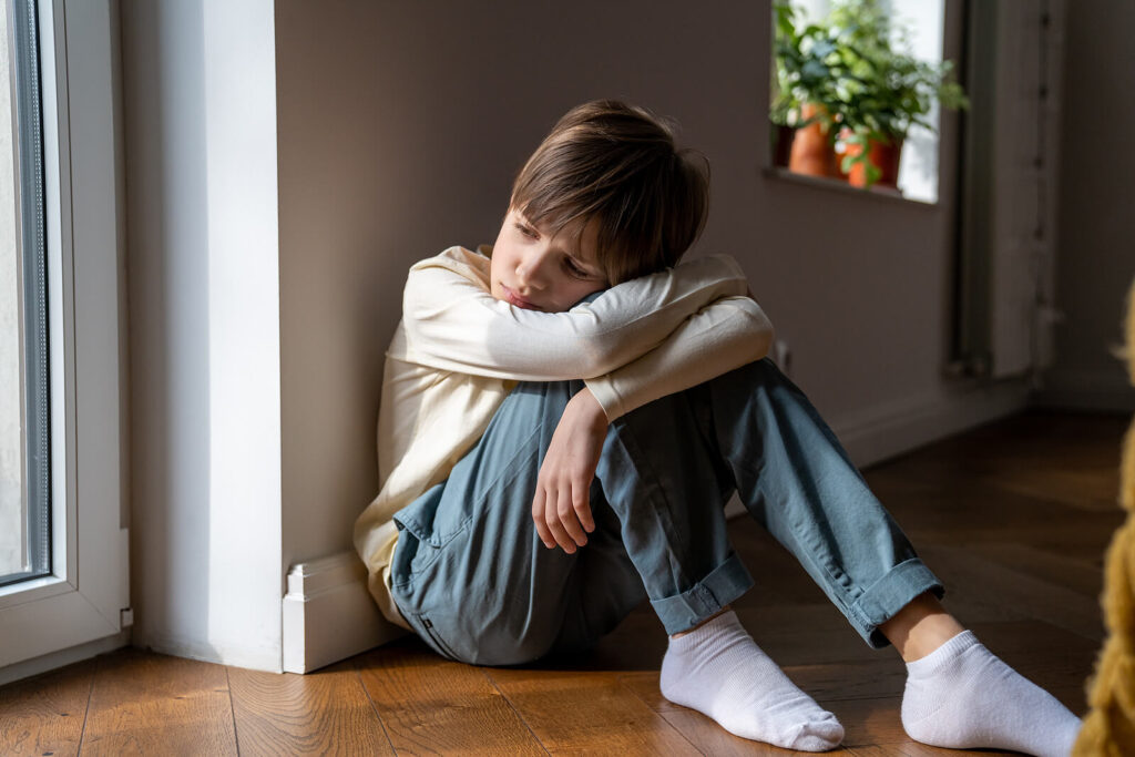 A young child sitting alone against a wall while resting their head. Therapy for children in Katy, TX can help your child build coping skills for anxiety. Our child therapists are here to help!