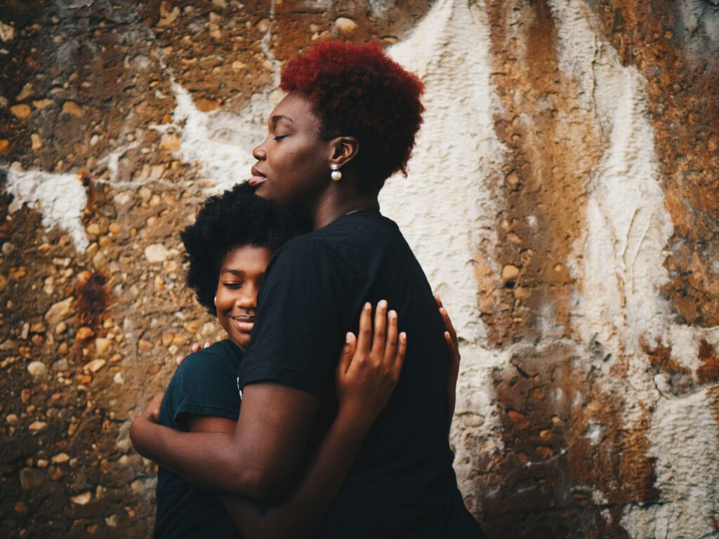 A mother hugging her daughter closely in a loving manner. Representing how child behavioral therapy in Katy, TX can help your family find peace. Get started with a child therapist today.