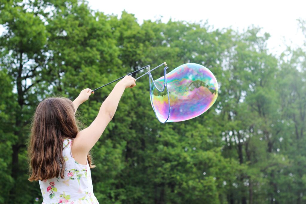 A young girl holding a big bubble in the air. Behavioral therapy for children in Katy, TX can help with tantrums, meltdowns & emotional dysregulation. Help your child thrive today!