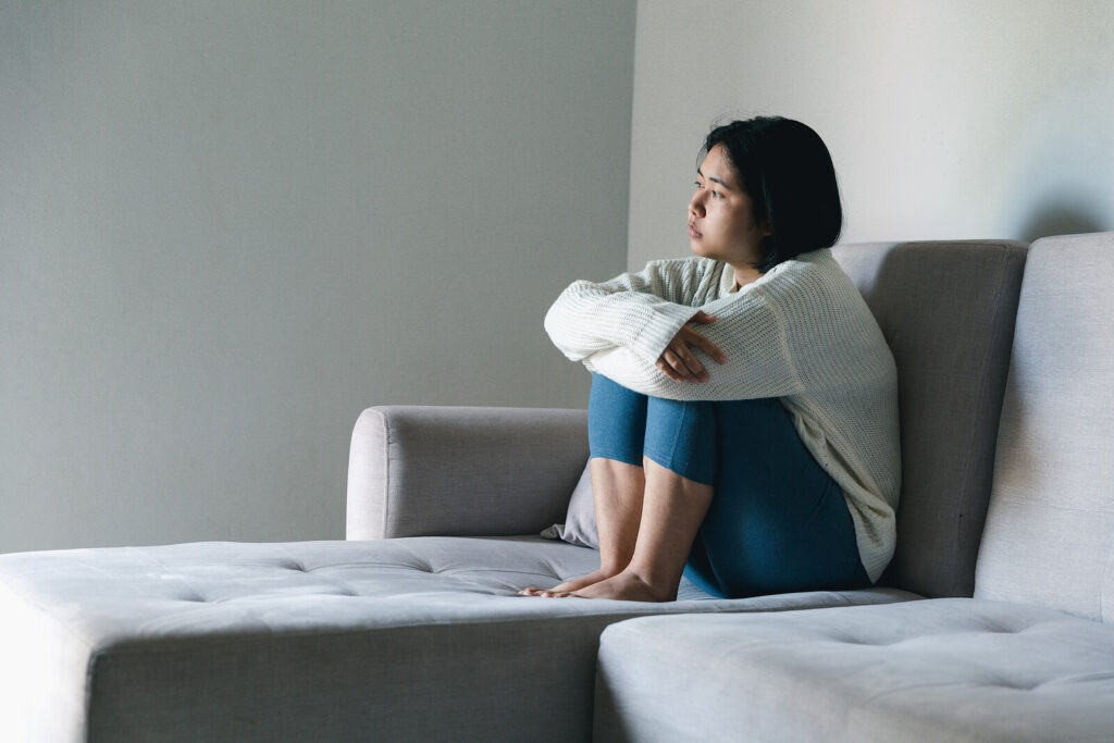 A young teen sitting alone on a gray couch while hugging her legs. Did you know we offer child therapy for anxiety in Katy, TX? Our therapists can help your family flourish. 