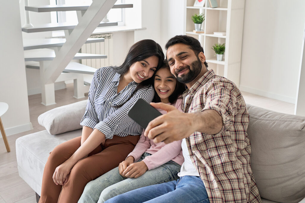 A happy family sitting on the couch posing for a picture together. Representing how counseling for teens in Katy, TX can help families find connection. Reach out today to get started. 