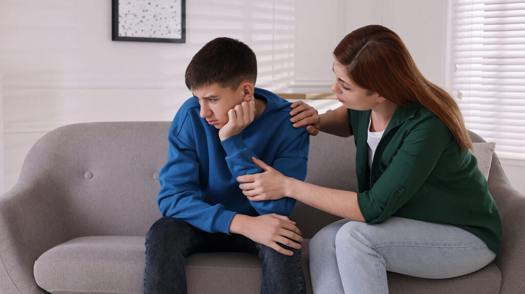 A teen boy sitting on the couch looking away from his mother while she sits beside him. Representing how teen anxiety can disrupt their every day life. Reach out to a teen therapist in Katy, TX today for help!