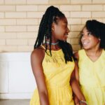 Two young black girls sitting on a bench wearing pretty yellow dresses. Is your teen struggling with anxiety? Our teen counseling in Katy, TX can help!