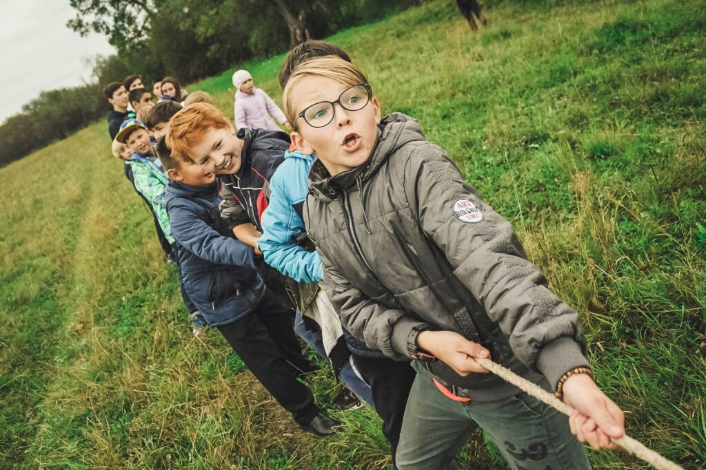 A group of diverse teen boys playing tug-of-war in a grassy field. If you're worried your child is in a toxic friendship, reach out to us today. Our child counseling in Katy, TX can help.