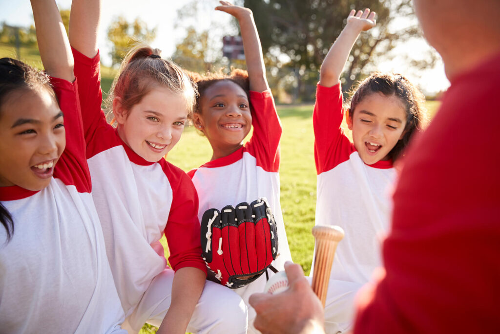 A red baseball team in a huddle cheering together. Representing how child counseling in Katy, TX can help your child build positive friendships. Reach out today to get started.