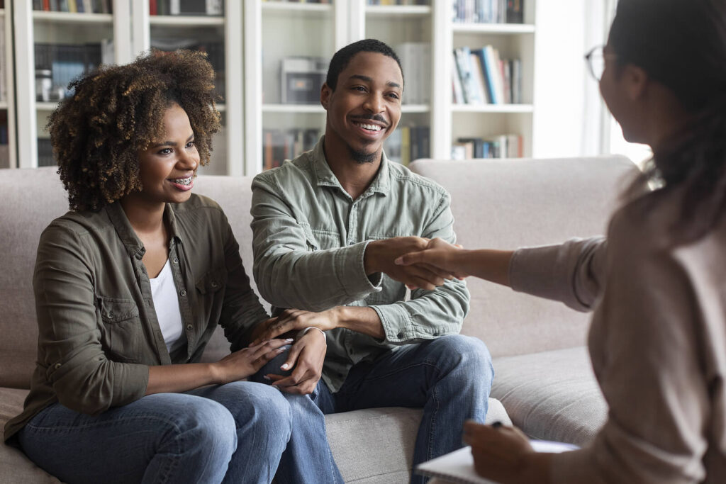 A black couple shaking hands with their couples therapist. Discover how couples therapy in Katy, TX can help you improve your connection & communication skills. Reach out today!