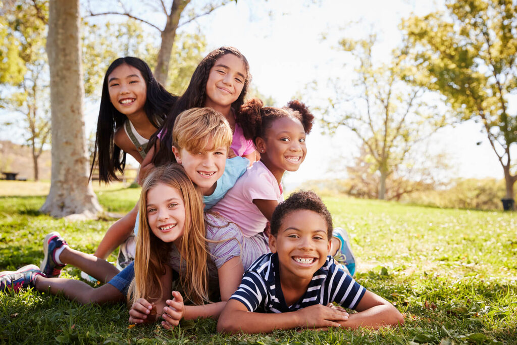 A group of diverse children piled on top of each other smiling for a picture. Worried about your child's friends? Discover how child's counseling in Katy, TX can help your child's friendships thrive!