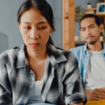 A woman sitting away from her partner on the couch looking upset. If your husband refuses to go to therapy, reach out to WHCC today. We offer couples therapy in Katy, TX & individual counseling.