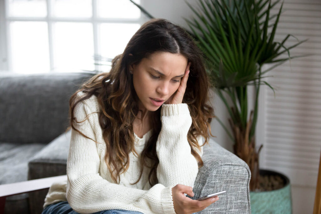 woman looking at phone | counseling katy | therapy katy | therapist katy, tx | 77084 | 77433 | 77095 An upset woman holding her head while she searches something online. Representing how finding the right therapist near you in Katy, TX is important for healing. Reach out today to learn more.