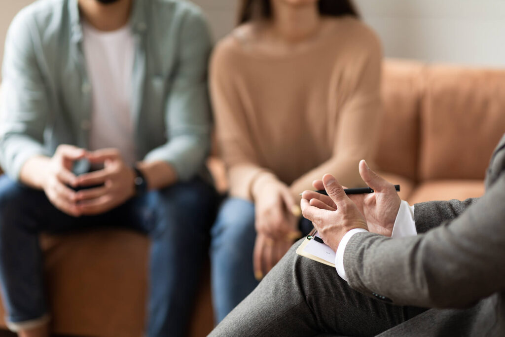 A therapist taking notes talking to a couple in therapy. Discover how therapy in Katy, TX can help you with relationship struggles, stress & more. Call us today to get started.
