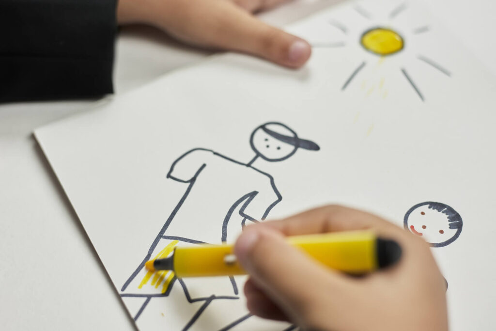 A child drawing stick figure people with an orange marker. Child therapy in Katy, TX can help with recent tragedies. Get support for the whole family today.