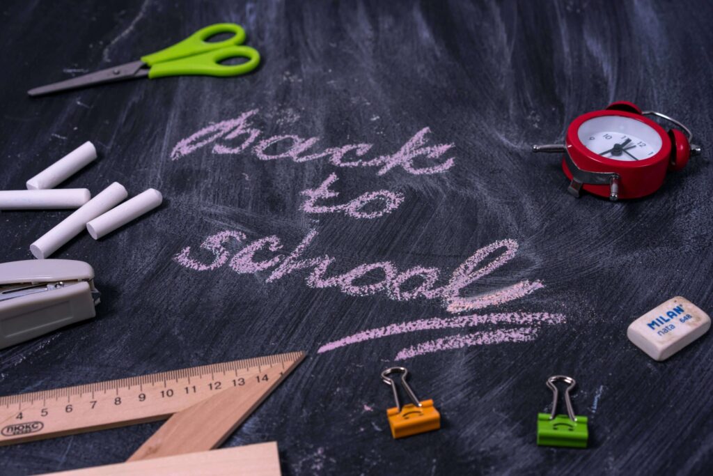 "Back to school" written on a chalkboard by school supplies. Child counseling in Katy, TX can help emotional regulation & anxiety. Reach out today!