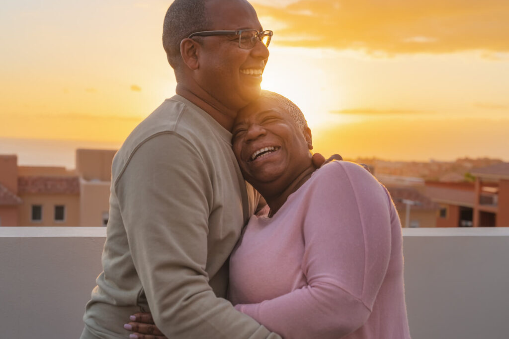 A biracial couple hugging each other on a rooftop during sunset. Adult therapy in Katy, TX is here to support individuals with anxiety, trauma, depression & more. Reach out for personalized support. 