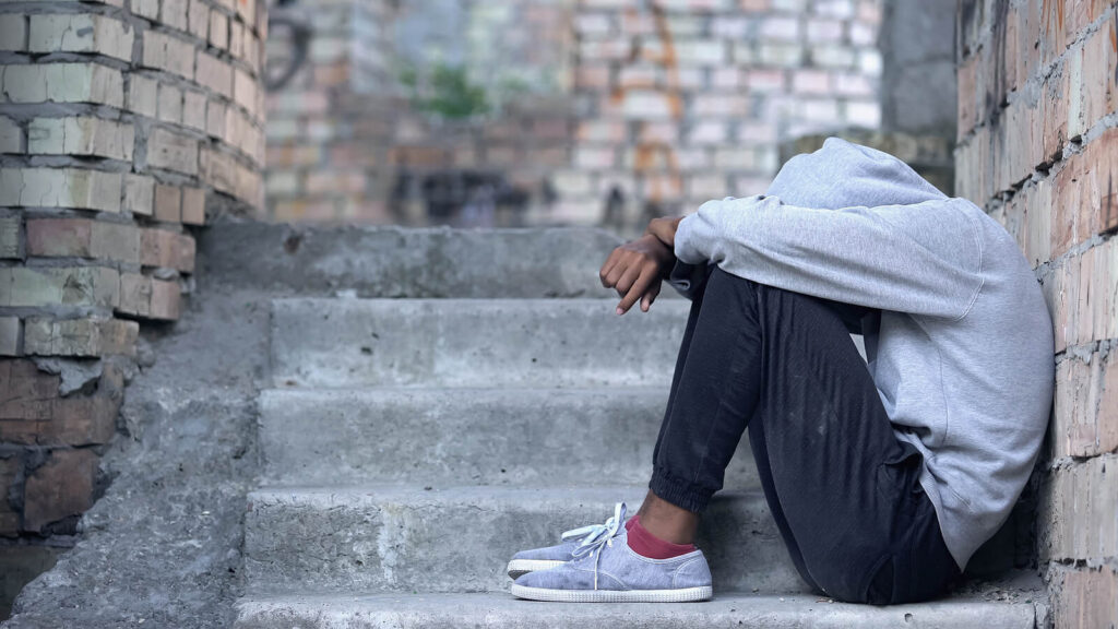 A teen male sitting alone on concrete steps with a hoodie over his head. If your teen engages in risky behavior, a teen therapist in Katy, TX can help. Discover more here.