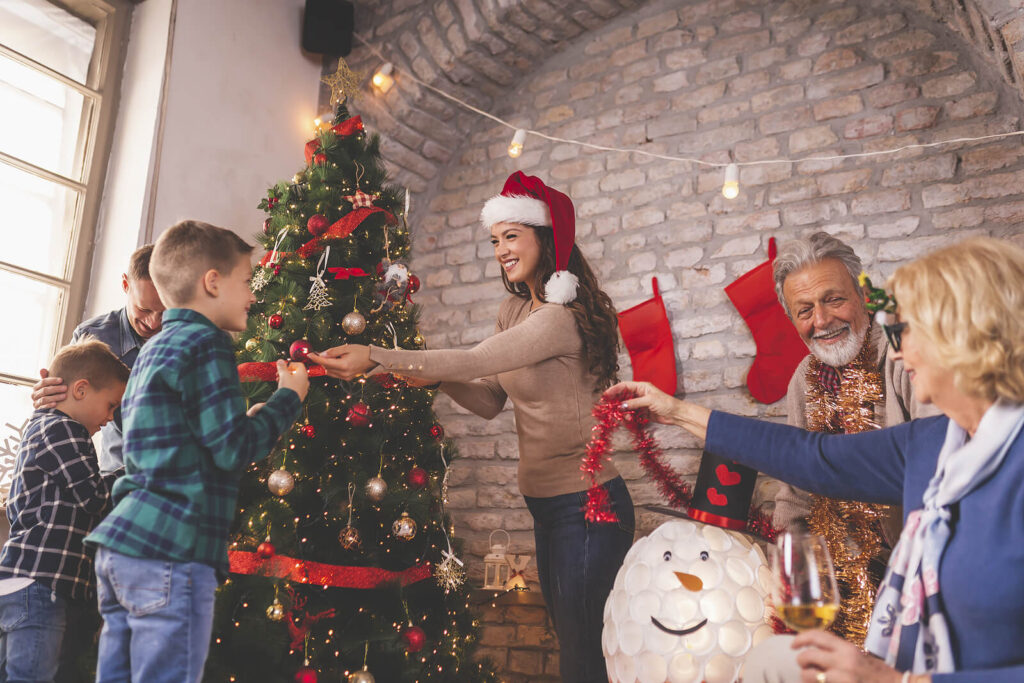 A family smiling while decorating a tree together in the living room. Counseling for women in Katy, TX is here to support you this holiday season. Reach out today.