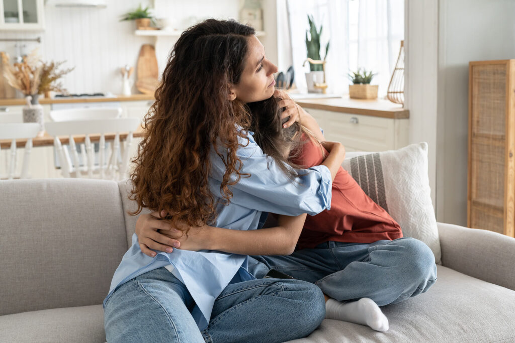 A mother hugging their teen on the couch as they sit close together. Representing how counseling for teens in Katy, TX can help you reconnect with your child. Learn more here!