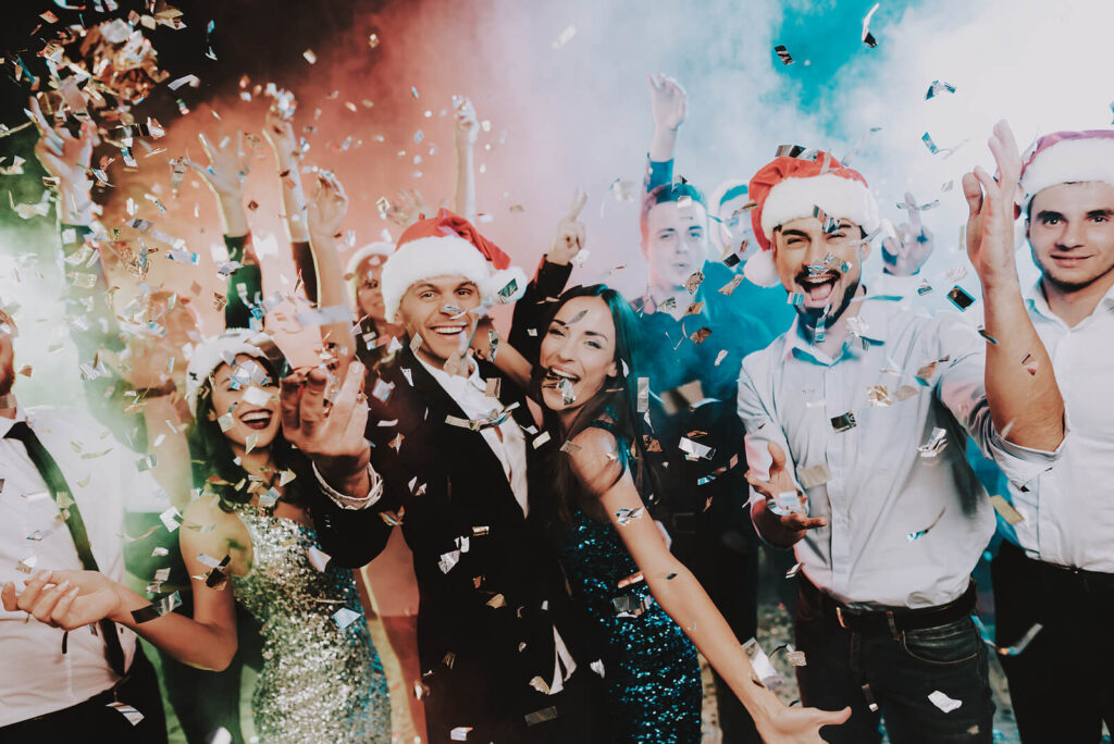 A group of adult friends celebrating New Years Eve with gold confetti. Adult therapy in Katy, TX can help you set resolutions that you can stick too. Learn more here!