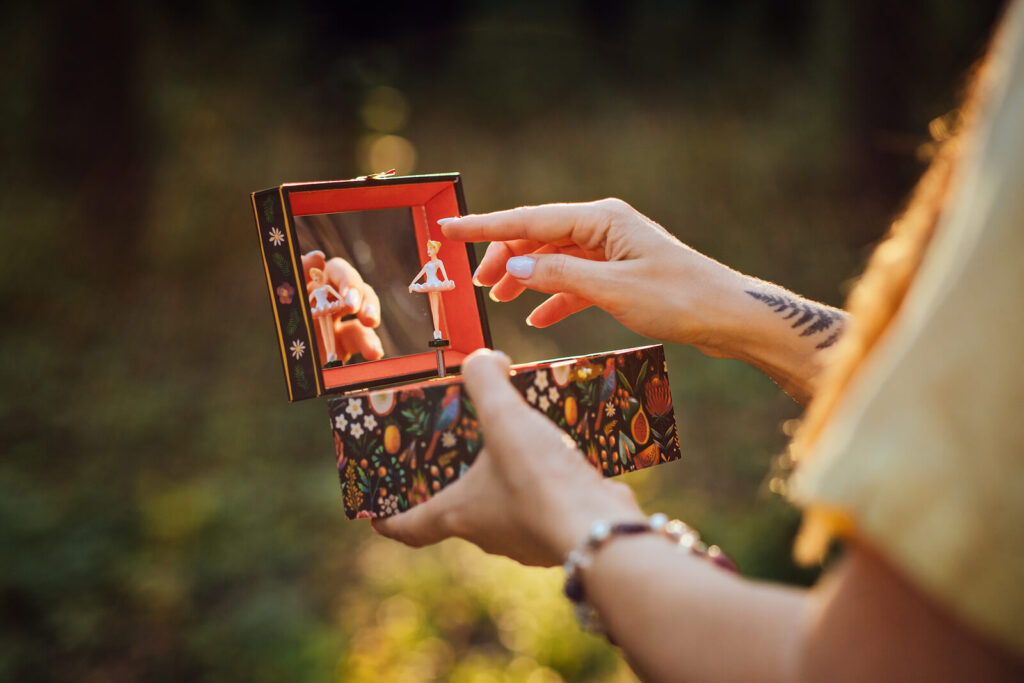 A woman with painted nails holding a colorful ballerina music box. Unresolved childhood trauma can creep into your adulthood. Get support with trauma therapy in Katy, TX. 