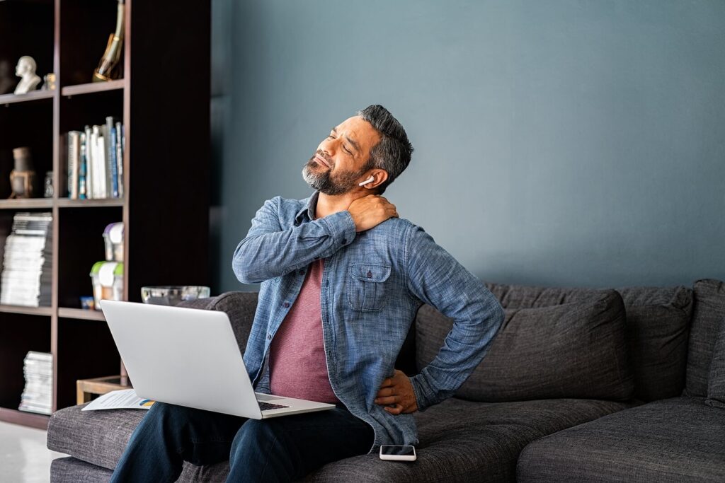 A middle-aged man with airpods grabbing his aching shoulder & backs. Discover how Katy therapy can help you navigate life challenges with greater confidence. 