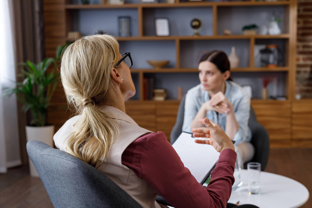 Over the shoulder view of a woman sitting down talking to a therapist. Discover how therapy in Katy, TX can help you navigate anxiety, trauma, work stress & beyond. Get paired with a compassionate therapist today.
