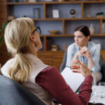 Over the shoulder view of a woman sitting down talking to a therapist. Discover how therapy in Katy, TX can help you navigate anxiety, trauma, work stress & beyond. Get paired with a compassionate therapist today.