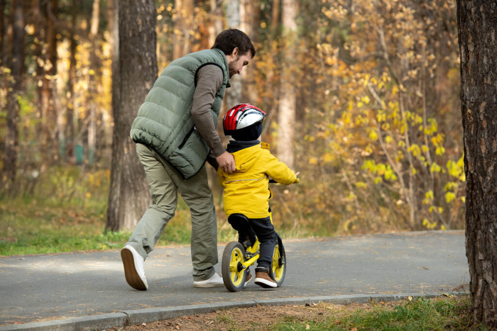A father teaching his young son to ride a bike outside in the fall. Adult trauma therapy in Katy, TX can help you learn to regulate your emotions. Discover how to get started here. 